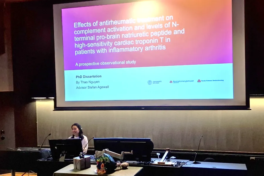 En person som sitter ved et bord med en projektorskjerm bak